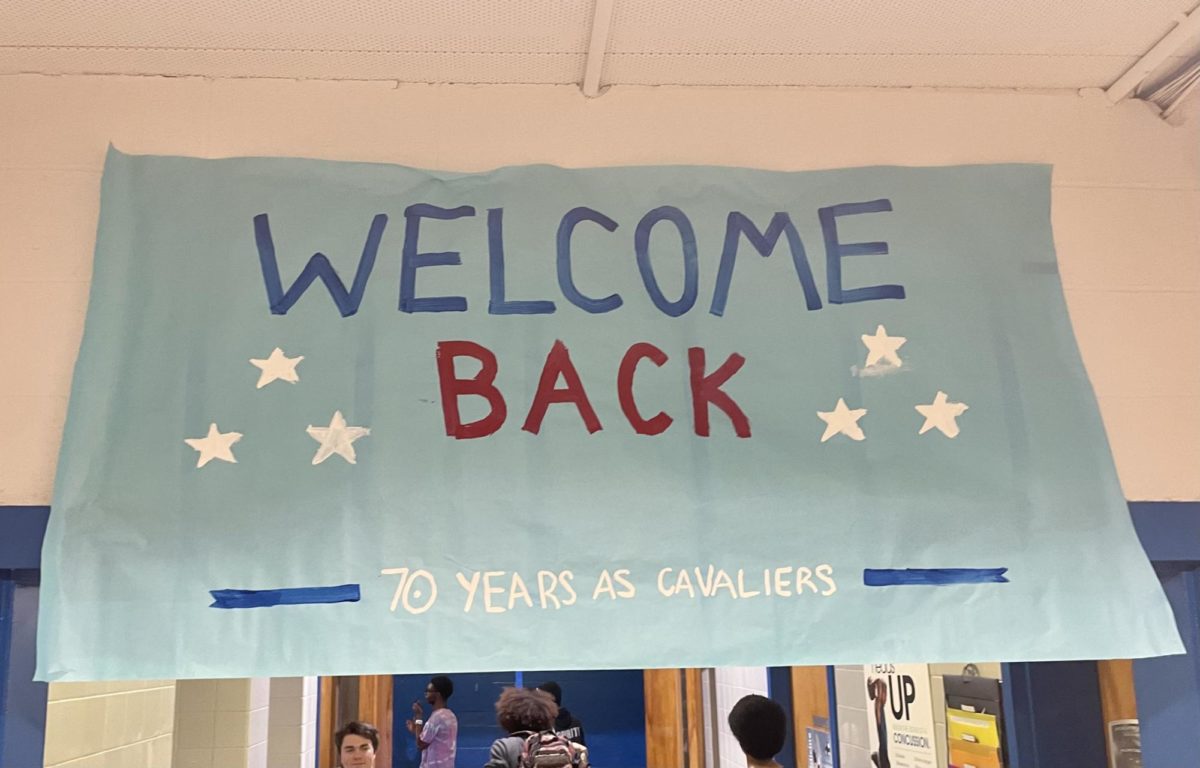 A banner reading Welcome Back greets students as they enter the first pep rally of the year. 