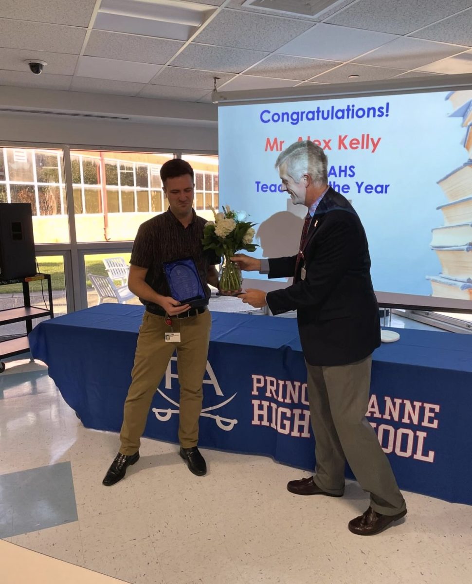 Orchestra teacher Alexander Kelly receiving teacher of the year award from Principal Todd Tarkenton.  